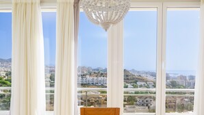Una habitación con ventanas amplias, una araña y una mesa de comedor con sillas.