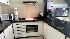 Una cucina compatta con forno integrato, microonde e macchina da caffè.