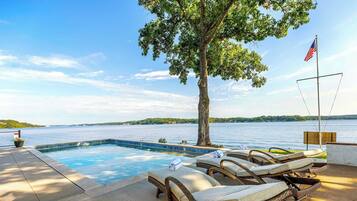 Un espace piscine avec des chaises longues, un drapeau et une vue sur un lac.