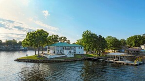A waterfront property with a large house featuring a covered porch, a dock, and a small pier. - Panoramic Paradise – Lakefront Home for 15 w/ Game Room, Pool (Rocky Mount)