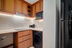 Une cuisine compacte dotée de meubles en bois, d’un four à micro-ondes encastré, d’un lave-vaisselle et d’un réfrigérateur en acier inoxydable.