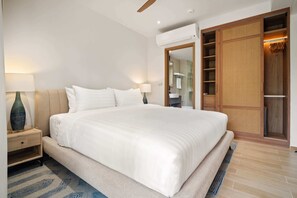 A modern hotel room with a large bed, a nightstand, a lamp, an air conditioning unit, and a walk-in closet.