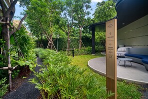 A garden with a wooden sign indicating a rest area and a garden walkway to the beach.