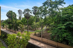 A balcony with a view of a lush garden and palm trees.