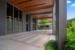 A modern building with large glass doors, a covered walkway, and a landscaped garden area. - Reef Residences, Three-Bedroom 3505 3B Premium (Choeng Thale)
