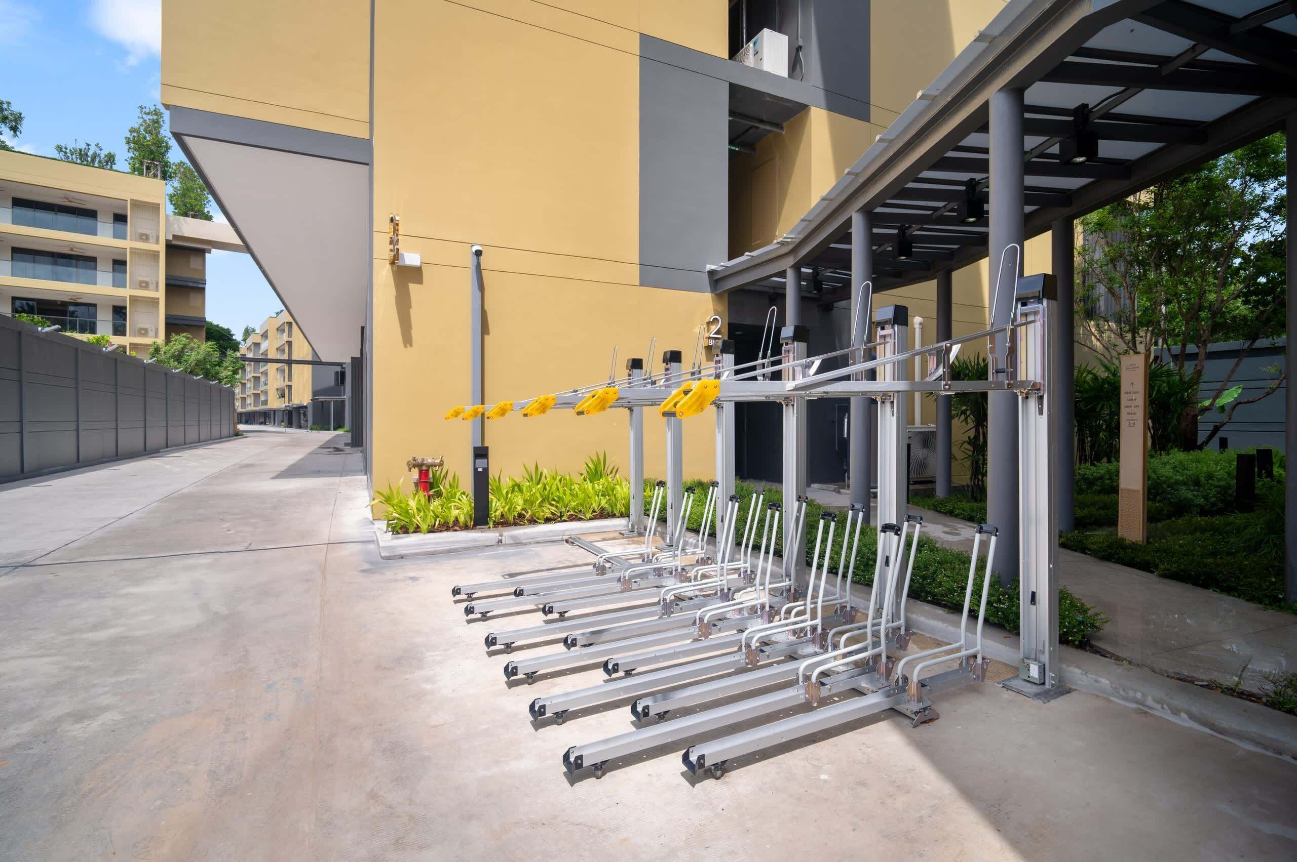 A row of outdoor exercise equipment near a building with a yellow facade.