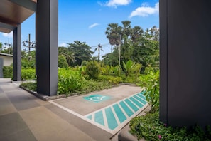 A covered outdoor area with a wheelchair-accessible path, surrounded by lush greenery and palm trees.