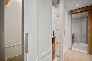 A modern hallway with white walls, a wooden door, and a built-in shelf unit.