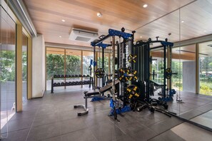 A modern gym with weightlifting equipment, large windows, and a clean, spacious layout. - Reef Residences, Three-Bedroom 3505 3B Premium (Choeng Thale)