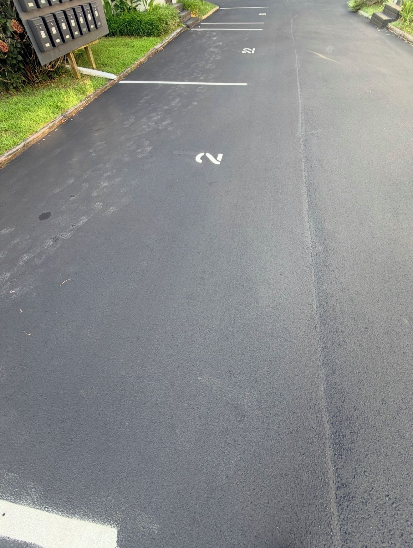 Een parkeerplaats met aangegeven parkeerplaatsen en een pijlpijl op het asfalt.