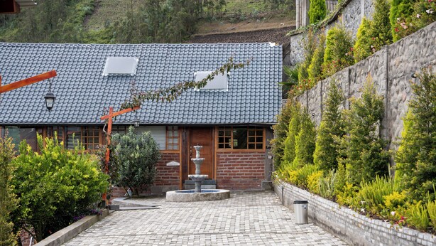 Un bâtiment traditionnel avec un toit en tuiles, une porte en bois et un mur de pierre orné de plantes.