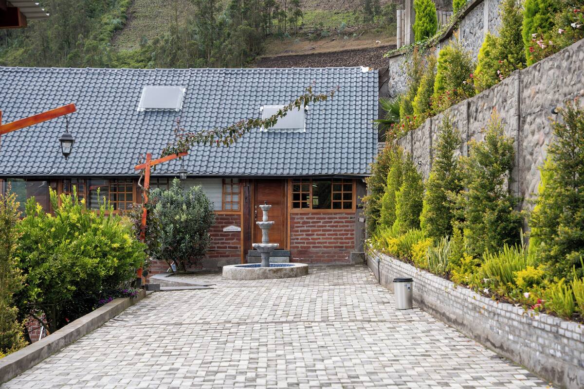 A traditional building with a tiled roof, a wooden door, and a stone wall with plants.