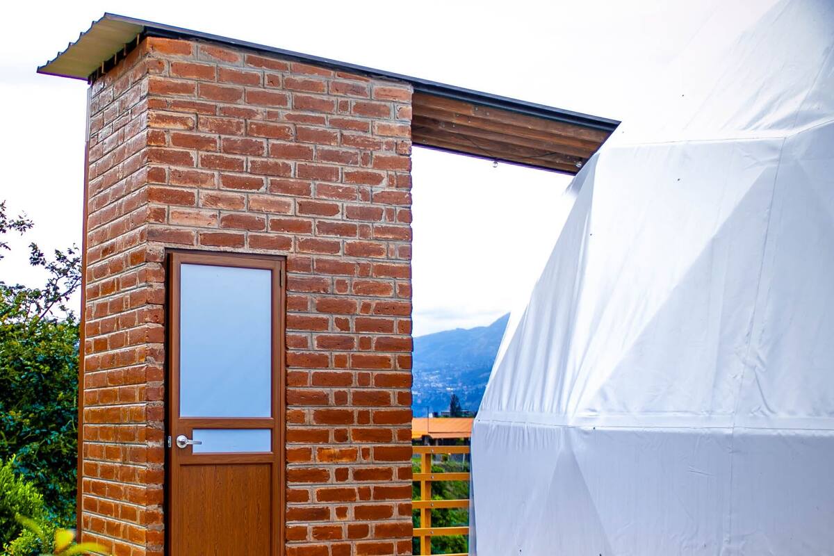 A brick building with a wooden door and a large white tent.