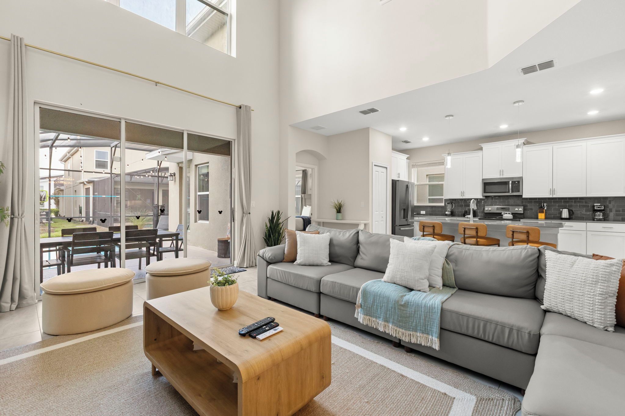 A spacious living room with a grey sofa, wooden coffee table, and a view of the kitchen and outdoor area.