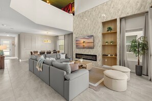 A modern living room with a gray sectional sofa, a flat-screen TV, and a dining area with a table and chairs. - Redecorated! 5 BD/ 5 BA/ Storey Lake (2762 BD) (Kissimmee)