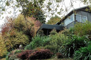 Una casa moderna rodeada de diversos árboles y arbustos.