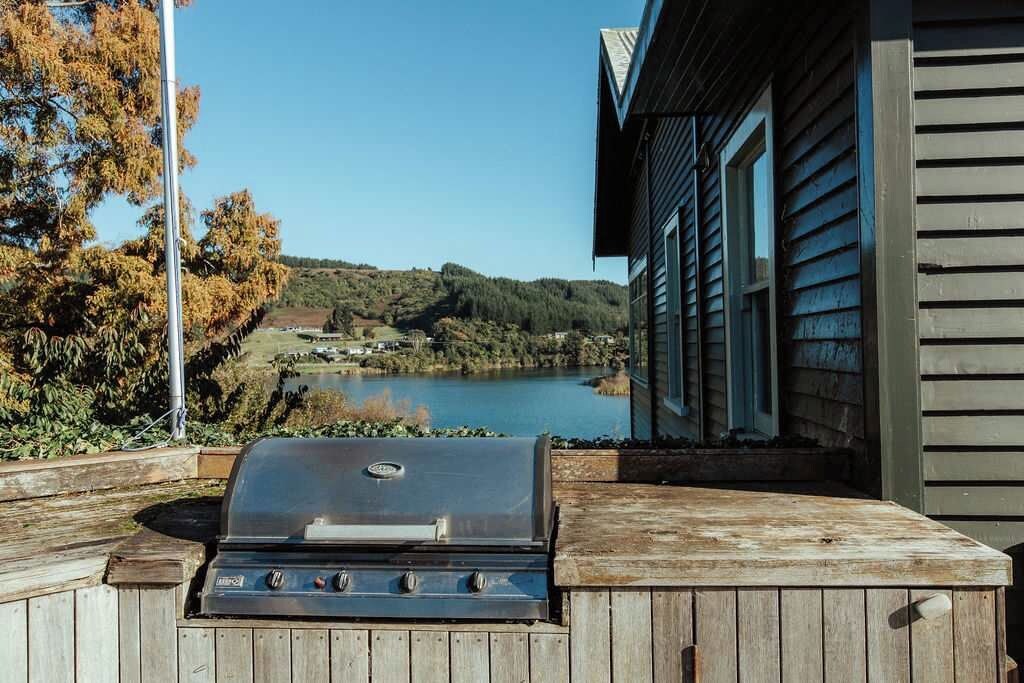 Ein Holzkohlegrill mit Blick auf einen See und Hügel im Hintergrund.