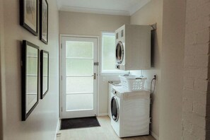 A laundry room with a washing machine, dryer, and a wall-mounted dryer.