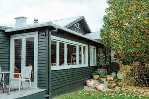 A house with a porch, a dining area with chairs, and potted plants.