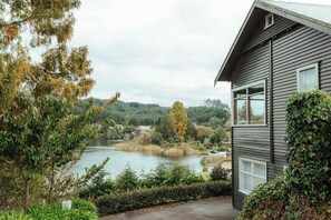 Una casa con vistas a un lago y colinas boscosas.
