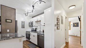 A modern kitchen with white cabinets, stainless steel appliances, and a granite countertop.