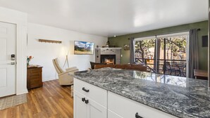 A modern kitchen with a large island, a fireplace, and a view of the outdoors.