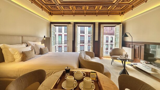 A hotel room with a large bed, two chairs, a small table with a tray of breakfast items, and a TV. - YOUROPO - Collection (Porto)