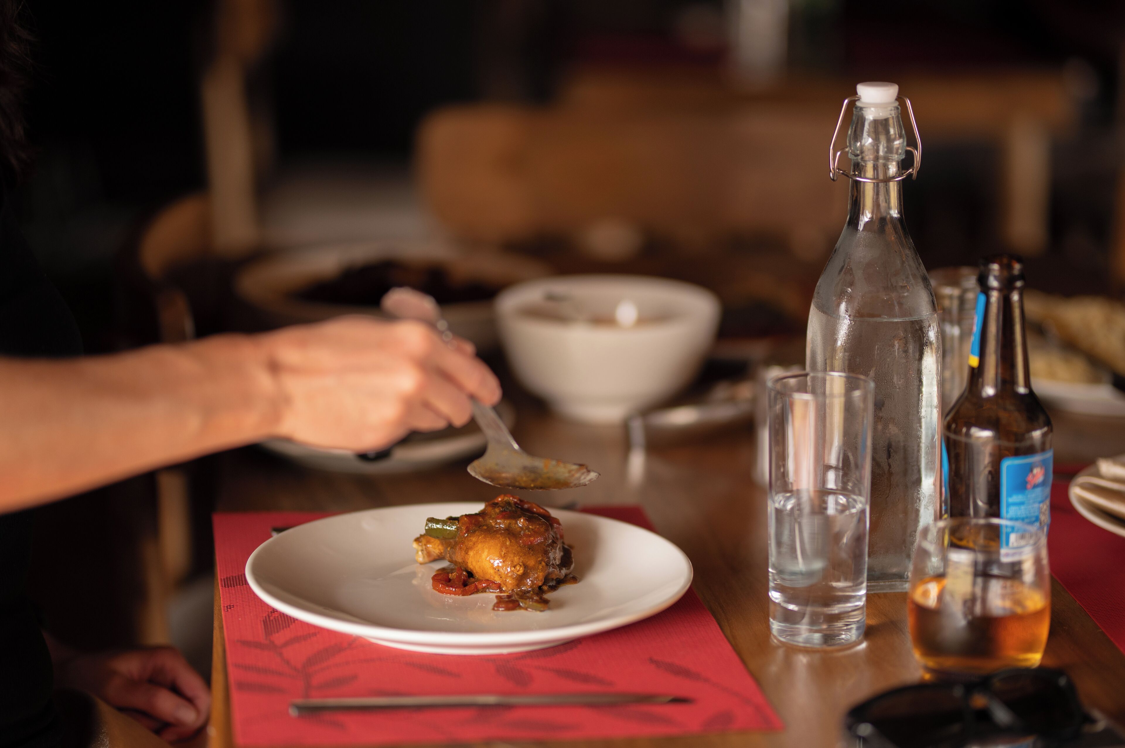 Une table à manger avec une assiette de nourriture, un verre d’eau et une bouteille.
