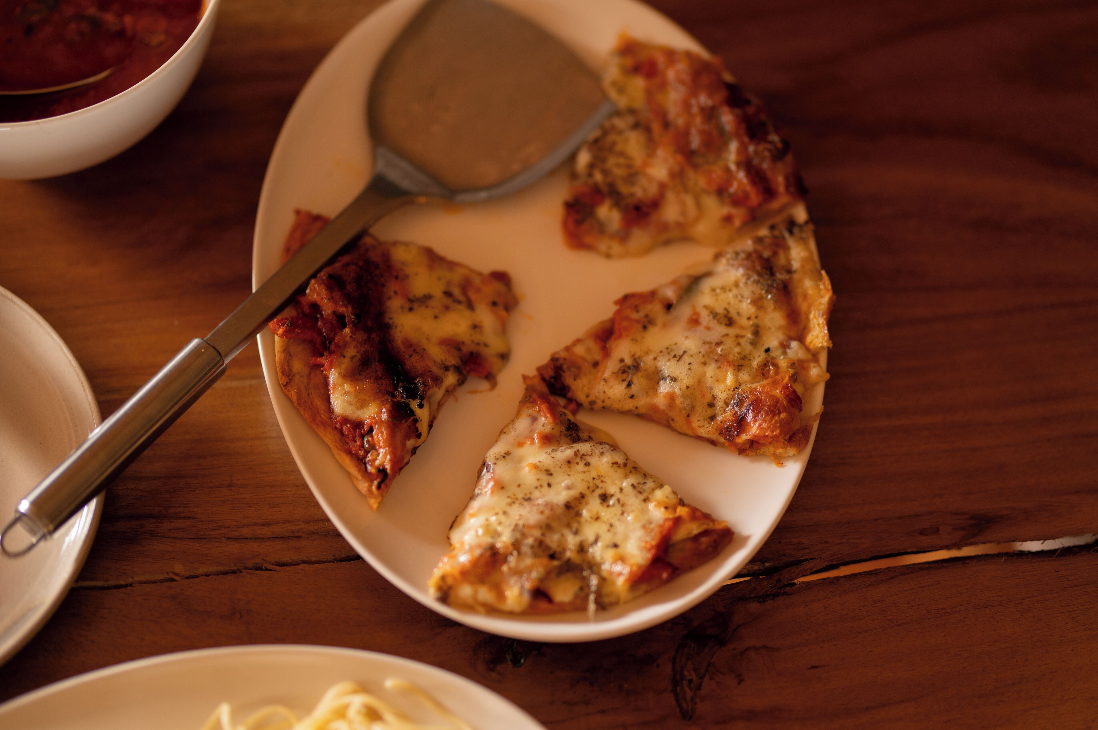 A plate with three slices of pizza on a wooden table.