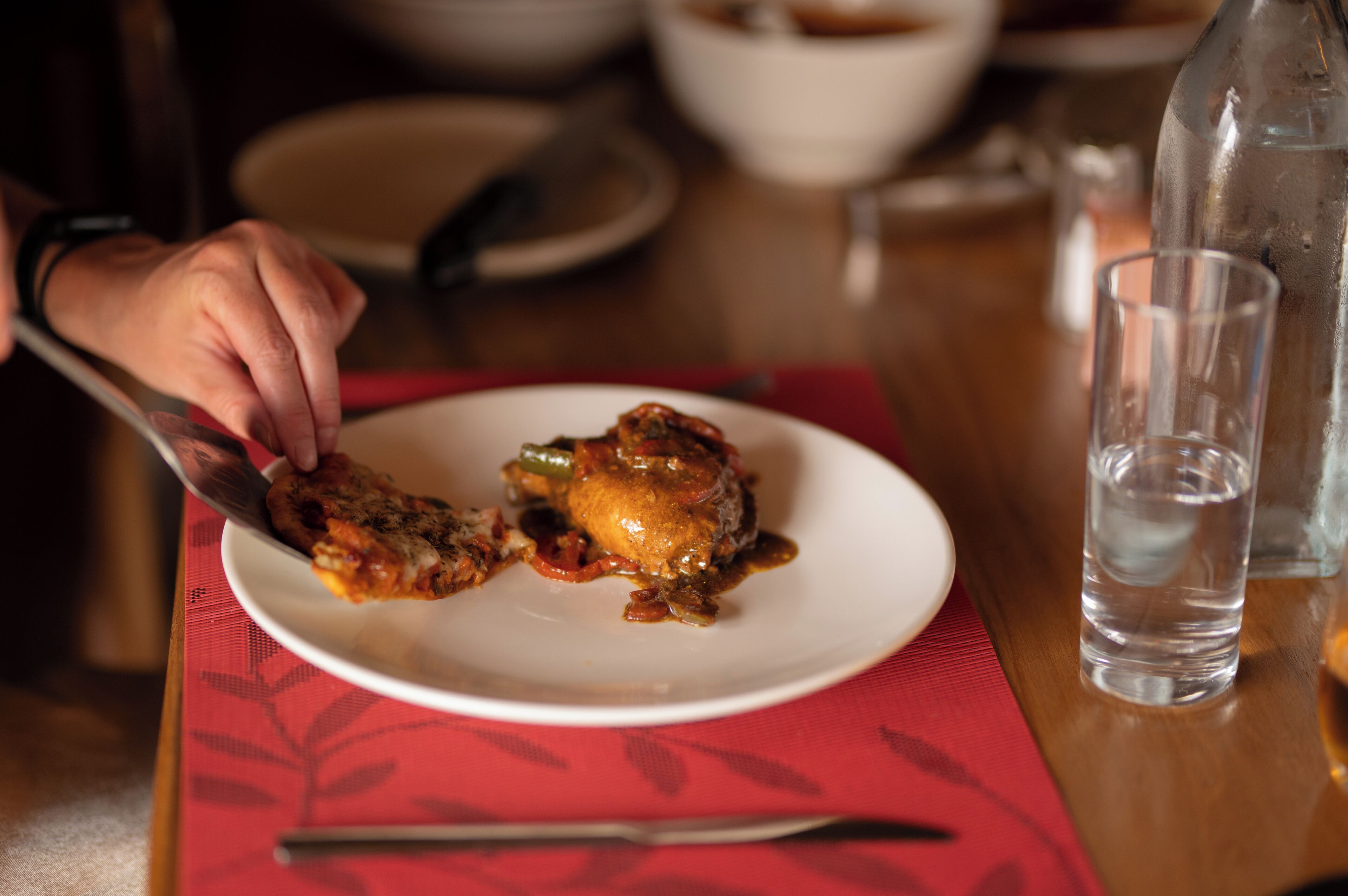 Una mesa de comedor con un plato de comida, un vaso de agua y un cuchillo.