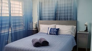 Une chambre à coucher avec un lit, une table de chevet, une lampe et un ventilateur de plafond.