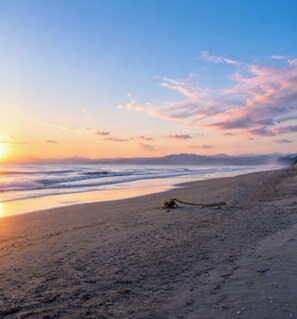 A beach with a wooden structure, waves, and a clear sky.