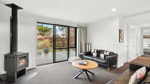 Una sala de estar moderna con chimenea, un sofá, una mesa de centro y vistas al exterior.