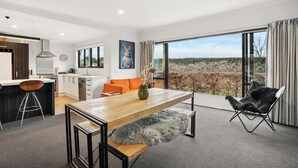 Una cocina moderna con armarios blancos, una campana extractora de acero inoxidable y una ventana con vistas a un jardín.