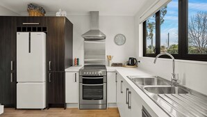 Una cocina moderna con campana extractora de acero inoxidable, horno empotrado, pileta doble y un amplio ventanal con vistas al exterior.