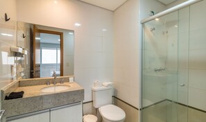 A modern bathroom with a granite countertop, a toilet, and a glass shower enclosure. - Brookfield Tower - BFT (Goiânia)