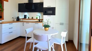 Una cocina moderna con armarios blancos, un microondas negro y una mesa de comedor redonda con sillas blancas.