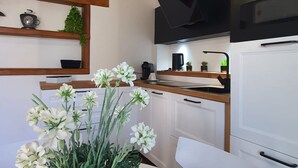 Una cocina moderna con armarios blancos, encimera de madera y campana extractora negra.