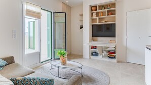 En moderne stue med sofa, sofabord og et tv-skab med hylder.