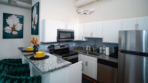 Una cocina moderna con armarios blancos, electrodomésticos de acero inoxidable y encimera de granito.