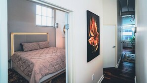 Un dormitorio con cama, ventana y un cuadro en la pared.