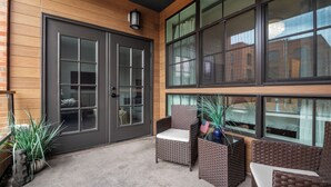 Un espace extérieur abrité, aménagé avec des meubles en osier et des plantes en pot.