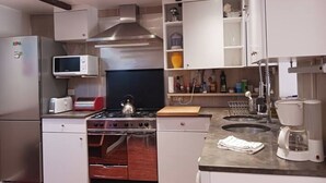 Una cocina moderna con electrodomésticos de acero inoxidable, horno empotrado, microondas y cafetera.