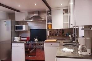 Una cocina moderna con electrodomésticos de acero inoxidable, horno empotrado, microondas y cafetera.