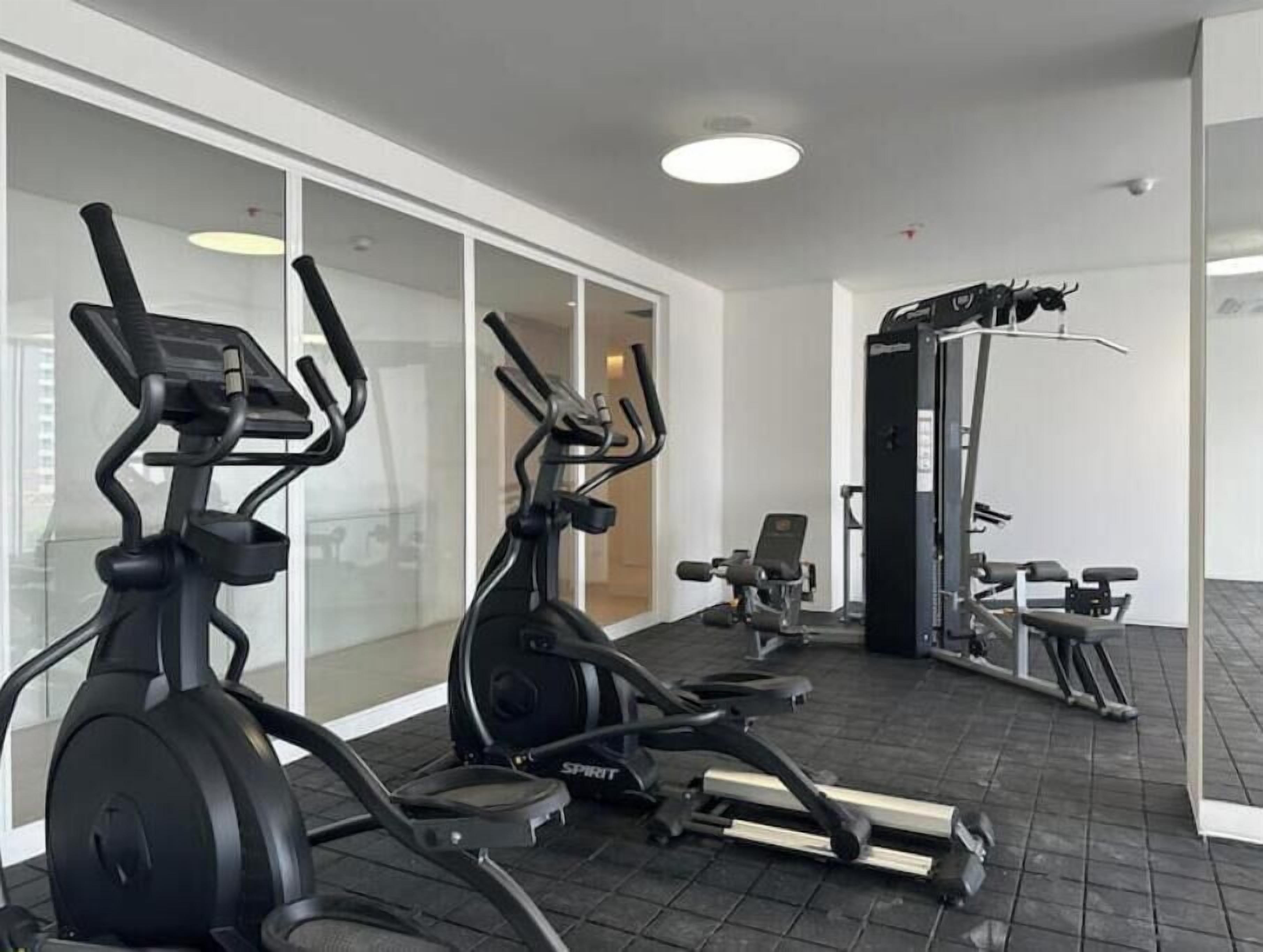 Un gimnasio con bicicletas estáticas, cinta de correr y máquinas de pesas.