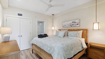 Quarto com cama, mesas de cabeceira, ventilador de teto e um quadro na parede.
