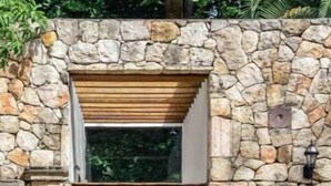 A stone wall entrance with a wooden door and a pool in the foreground. - Luxurious and Private Hacienda near Merida (Fraccionamiento Chuntuak, Molas)
