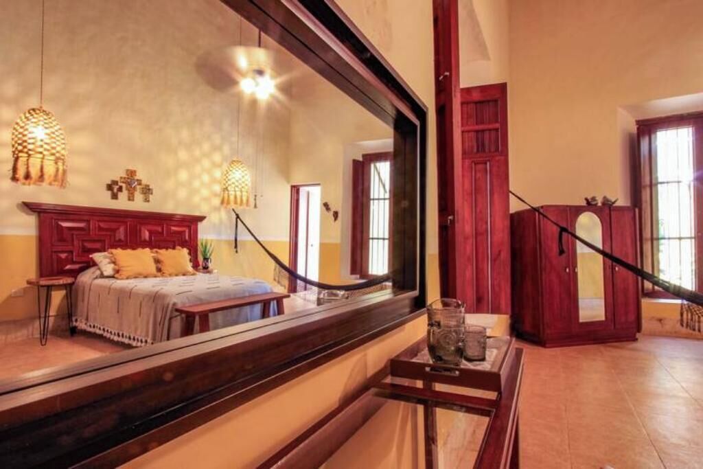 Une pièce comprenant un lit, un grand miroir et une armoire en bois.