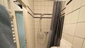 Un baño pequeño con bañera, ducha y lavamanos.