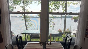 A dining area with a table set for four, overlooking a lake.